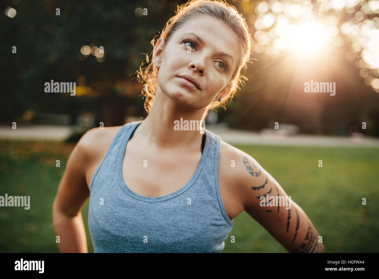 Close up portrait of fit woman standing outdoors and looking away. Confident fitness model in park. Stock Photo