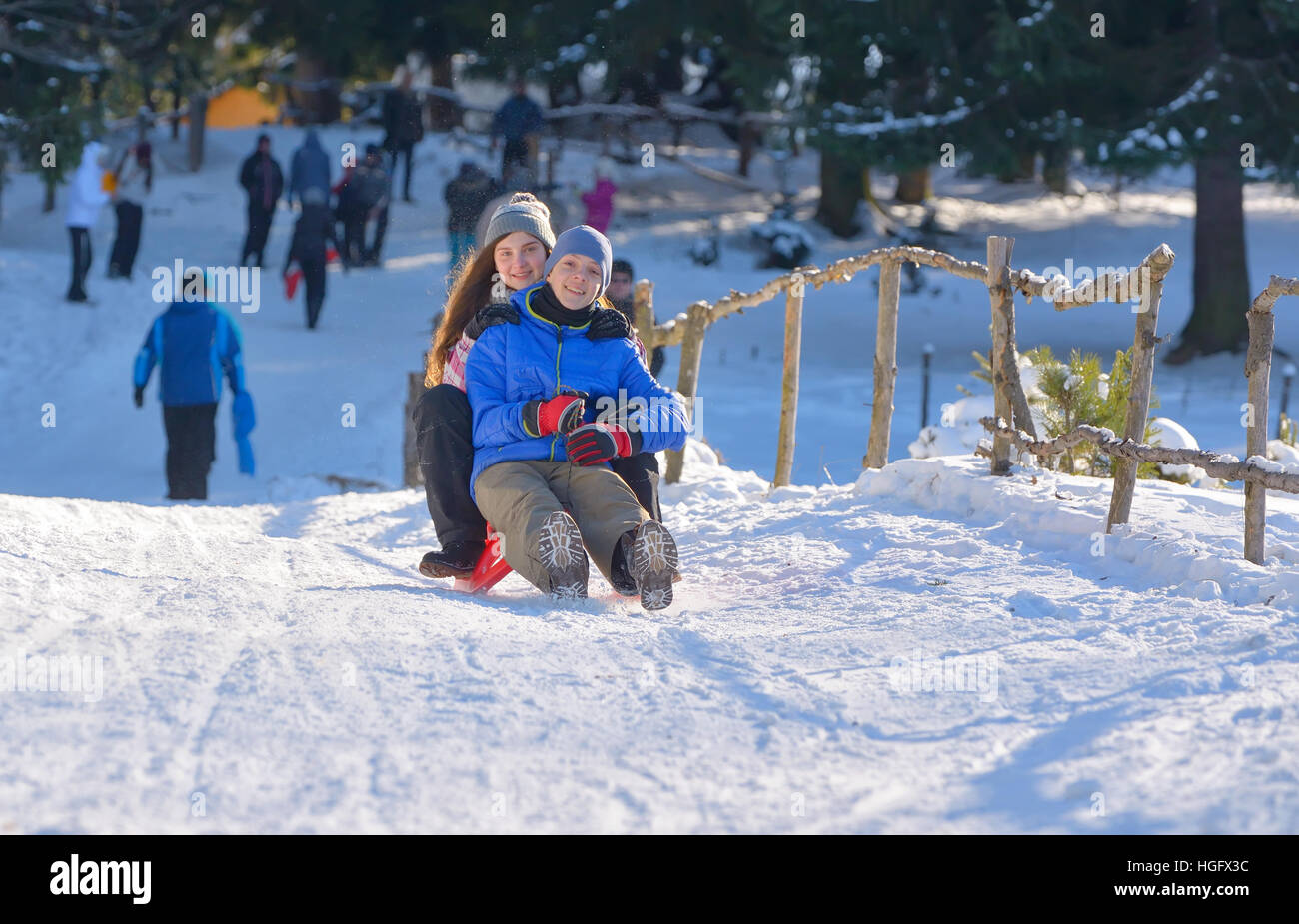 teenagers slide downhill in wintertime Stock Photo