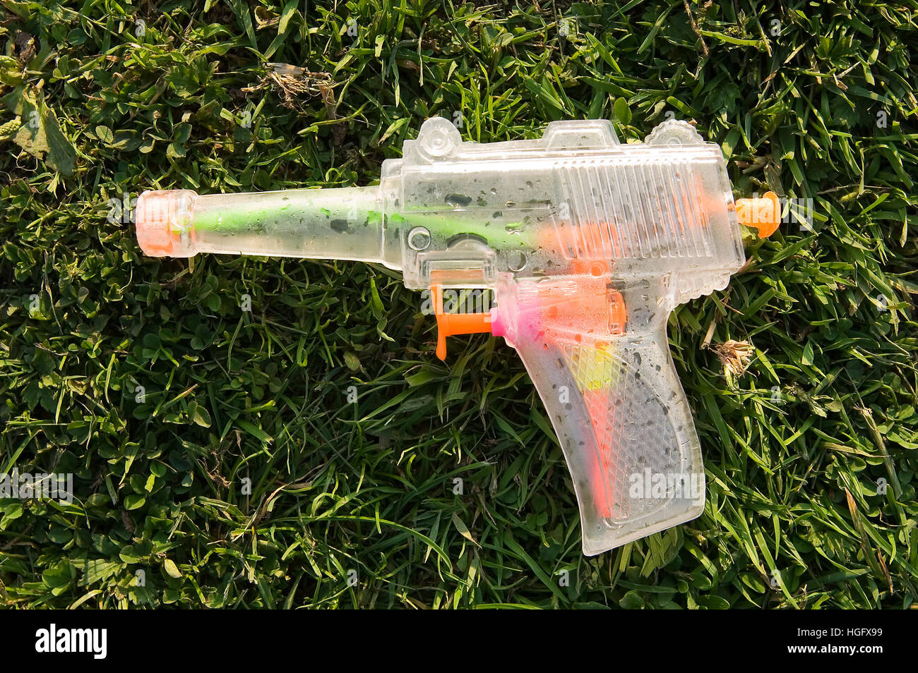 Child's toy water pistol lies discarded on grass Stock Photo
