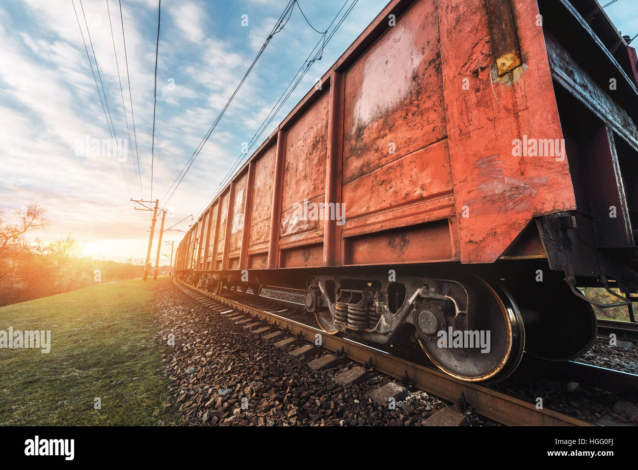 Railway station with cargo wagons and train against sunny sky in the evening. industrial landscape. Railroad with vintage toning Stock Photo