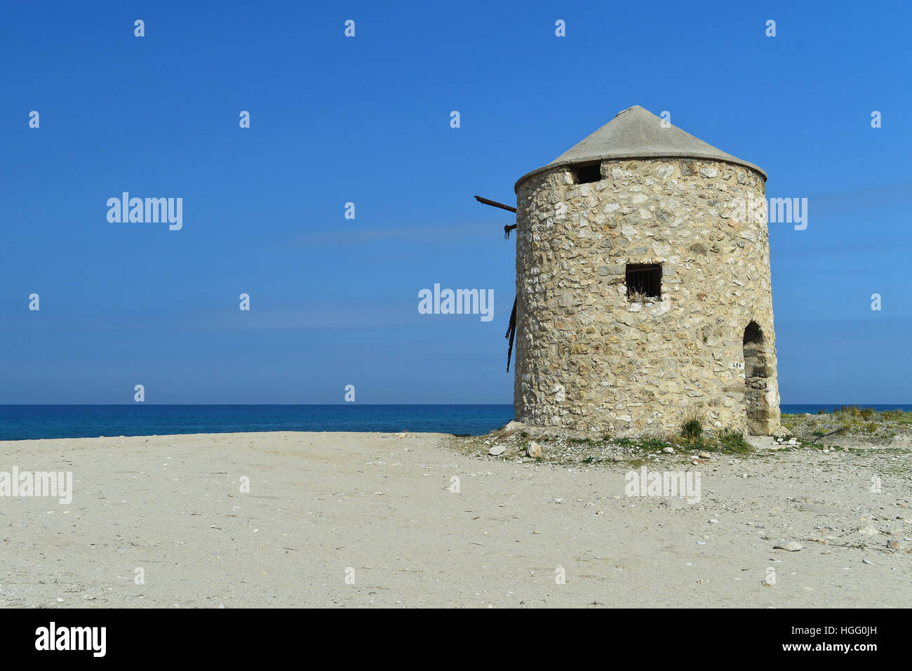 Old abandoned stone-built windmill on the sandy beach of Lefkada, Greece Stock Photo