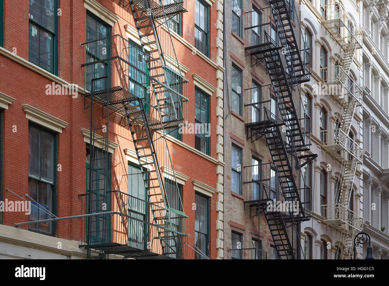 Typical building facades with fire escape stairs, sun beam in Soho, New York Stock Photo