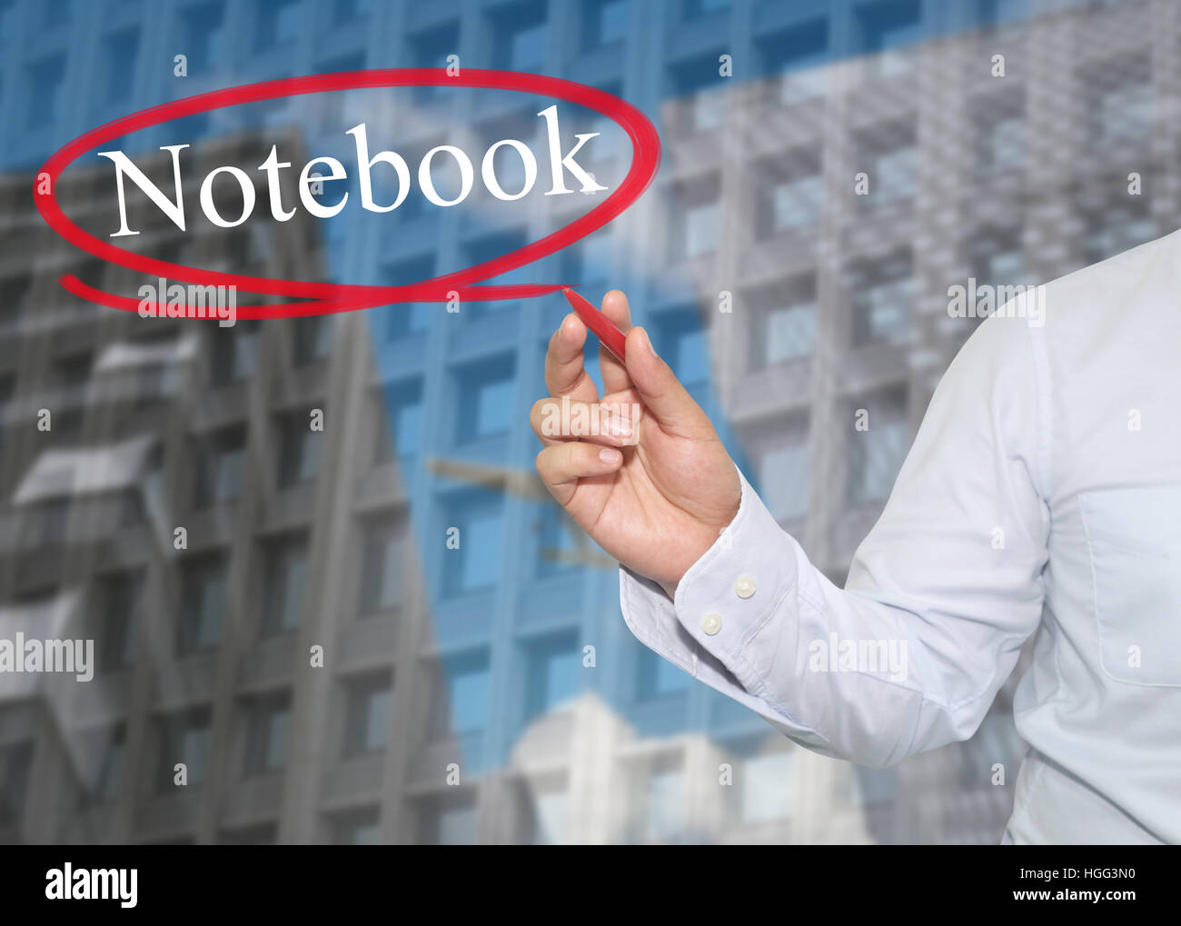 Hand of young businessman write the word Notebook on skyscrapers background,concept of Apply to promote your business or work presentations. Stock Photo