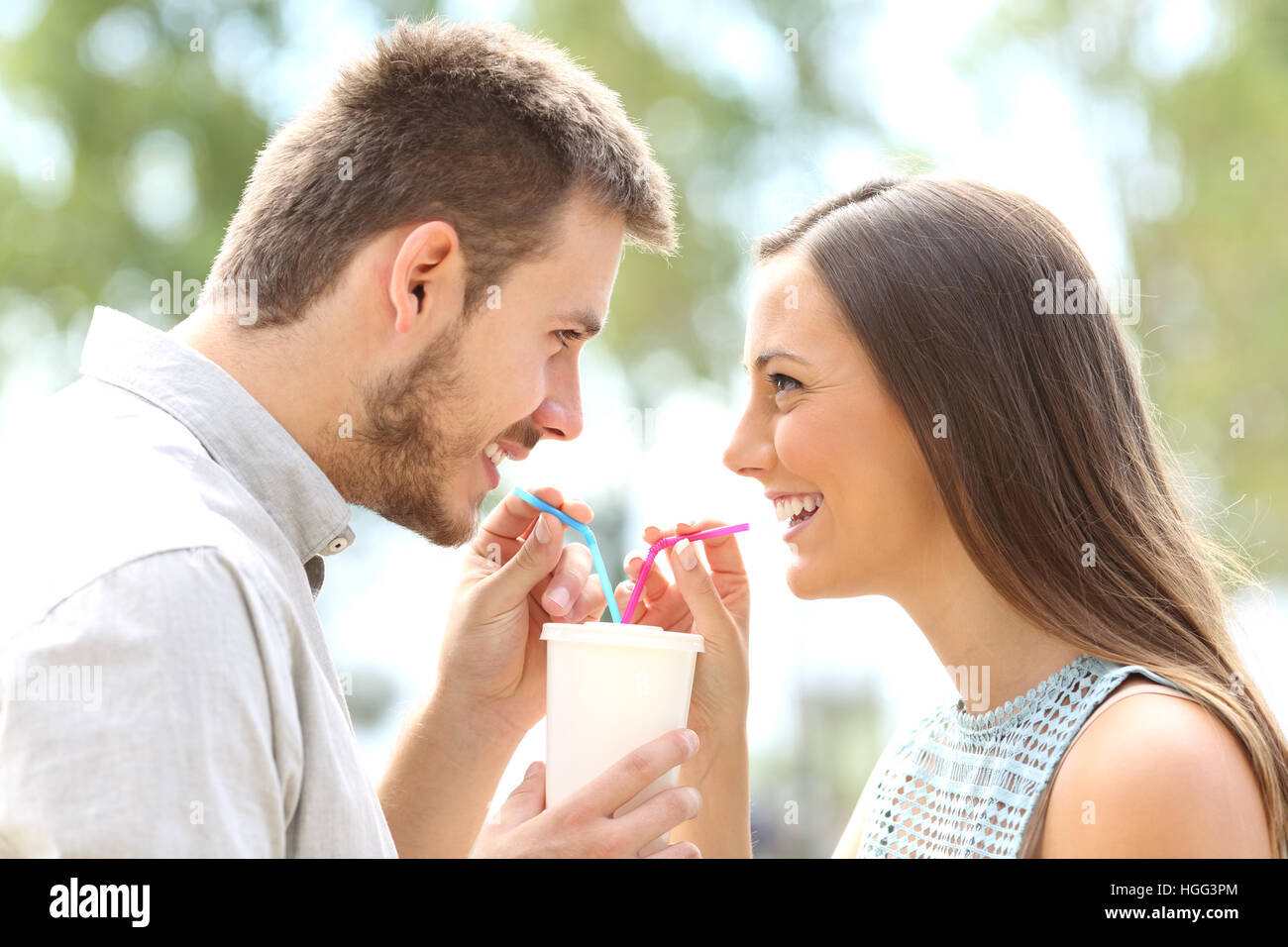 Side view of a happy couple falling in love and sharing a drink Stock Photo
