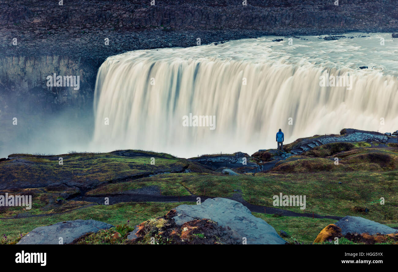 Tourist admiring view of falling water of the most powerful waterfall in Europe - Dettifoss. Jokulsargljufur National Park Stock Photo