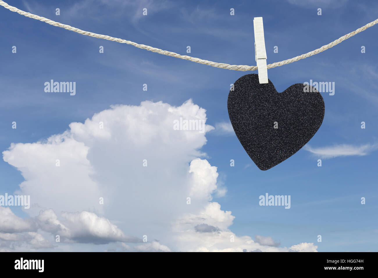 Black Heart hung on hemp rope on blue sky background and have copy space to manage the text you want. Stock Photo