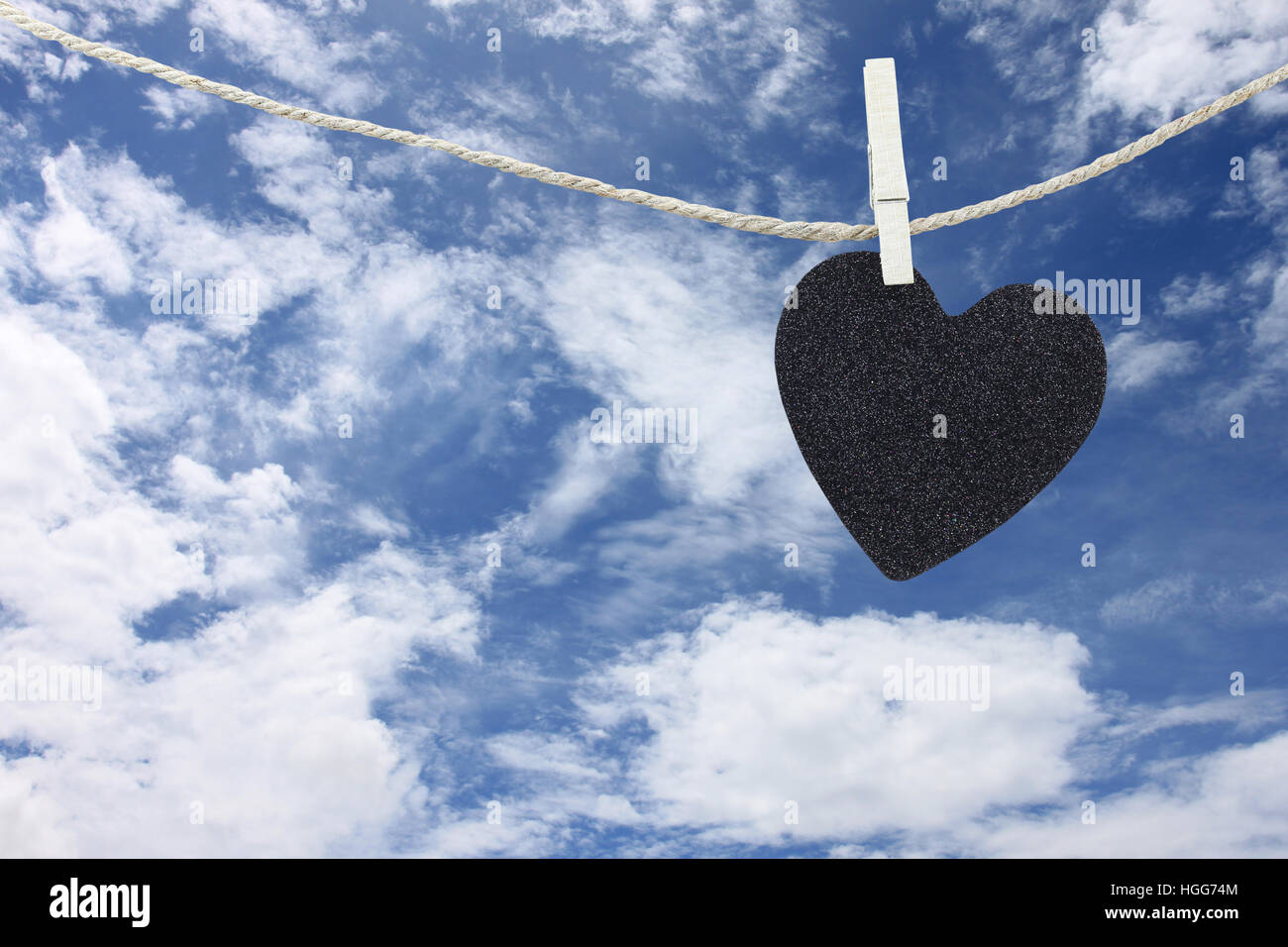 Black Heart hung on hemp rope on blue sky background and have copy space to manage the text you want. Stock Photo