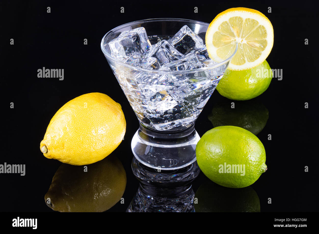 Sparkling beverage in a martini glass with lemons and limes on a black background Stock Photo
