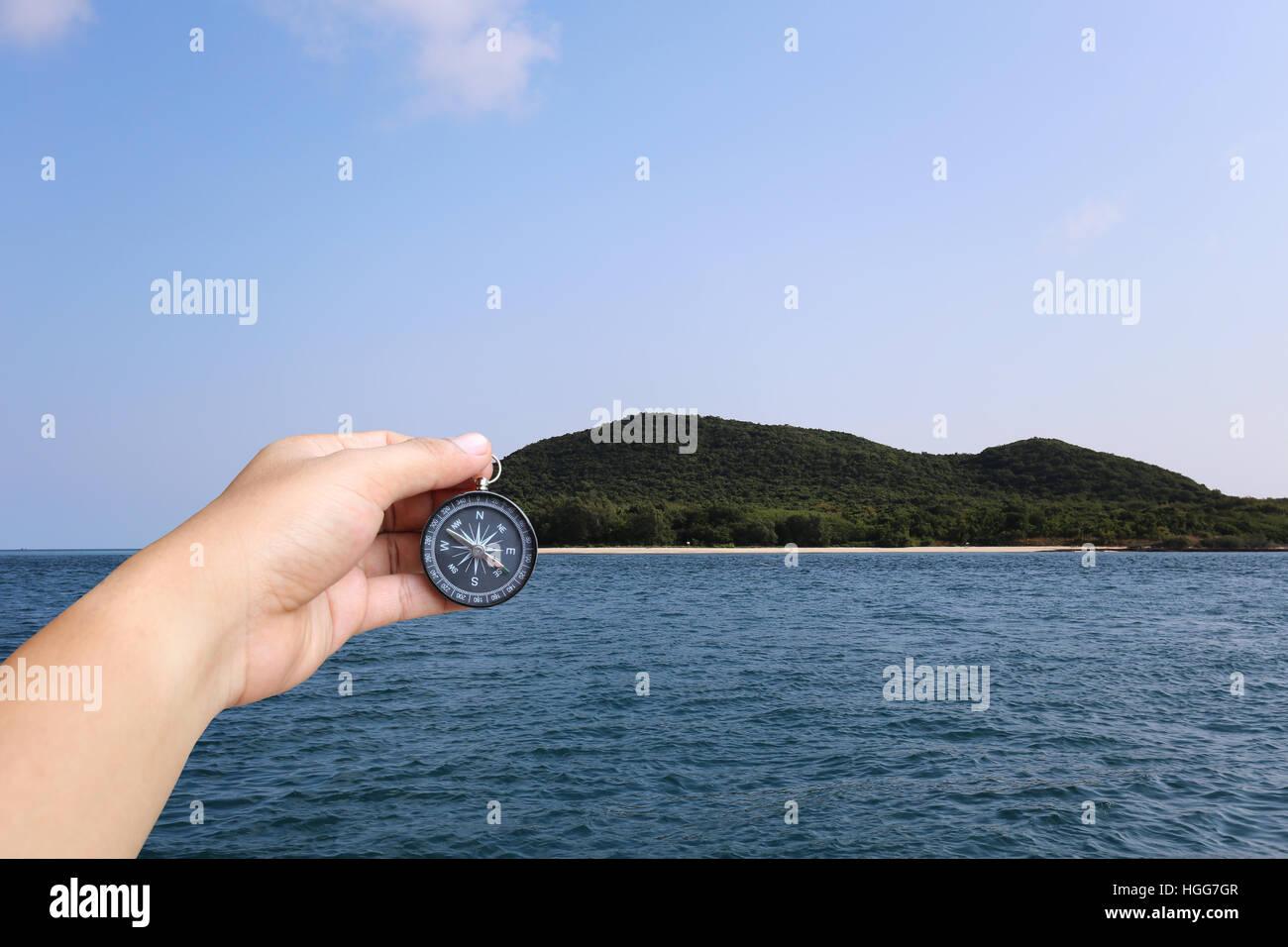 Hand of man holding a compass and sea island view,concept of journey at Ocean and targeted. Stock Photo