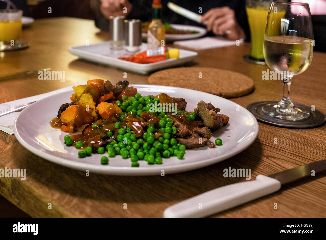 Evening meal, dinner of roast lamb, gravy, peas and vegetables & glass