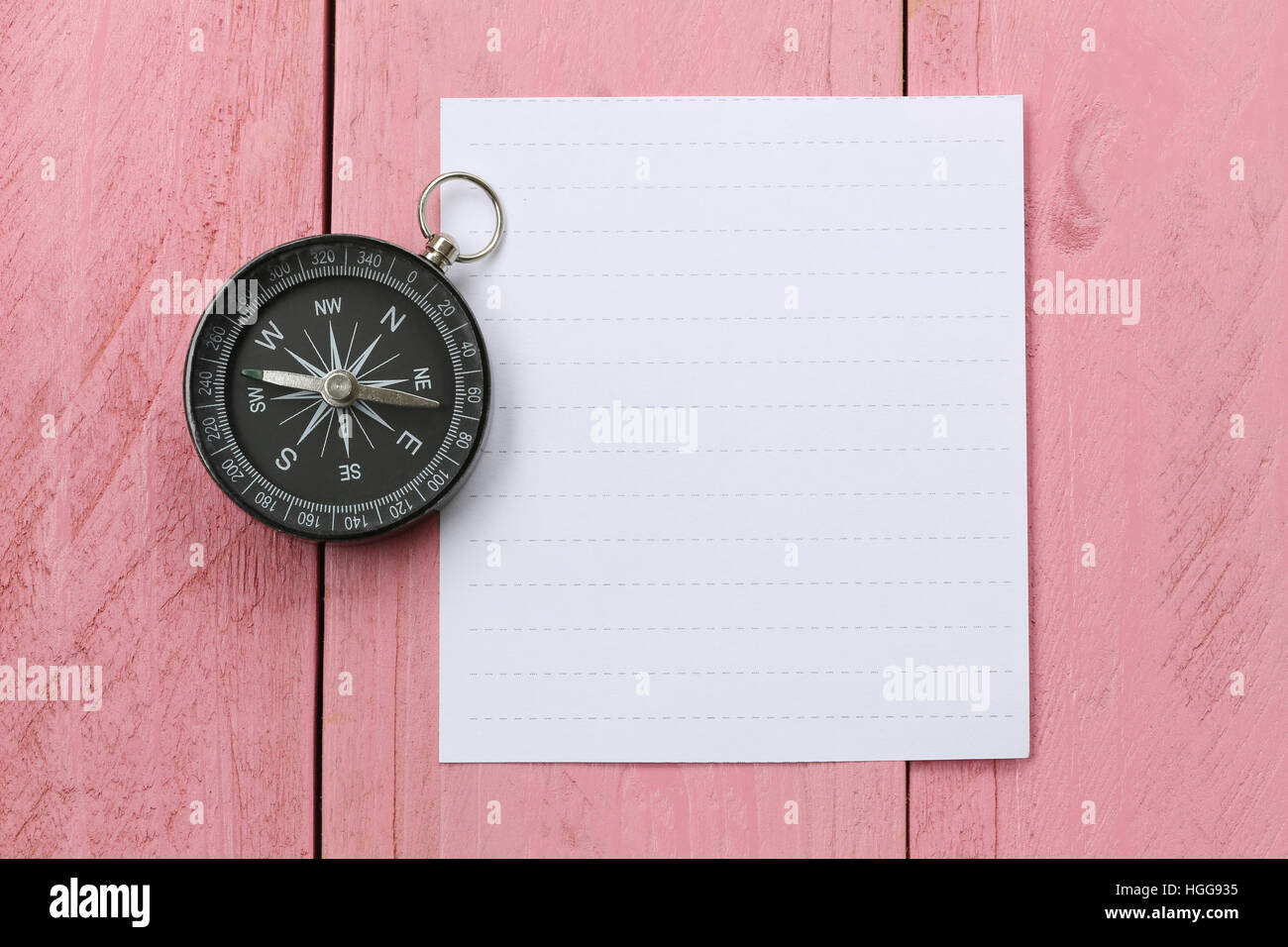 Compass and note paper on the pink wooden floor,concept of traveling and trekking. Stock Photo