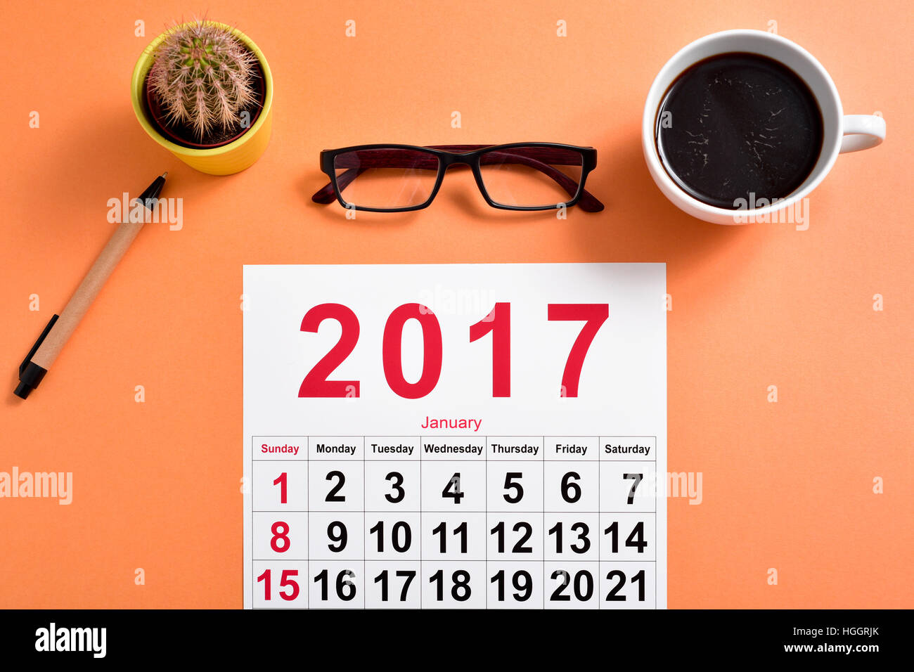 high-angle shot of a 2017 calendar, a pair of eyeglasses, a pen, a cactus and a cup of coffee on an office desk Stock Photo