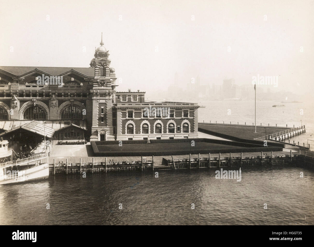 View of part of the front facade of the Immigration Station; the New York skyline is barely discernable through the haze in the background   - Ellis Island Immigration Station 1902-1913 Stock Photo
