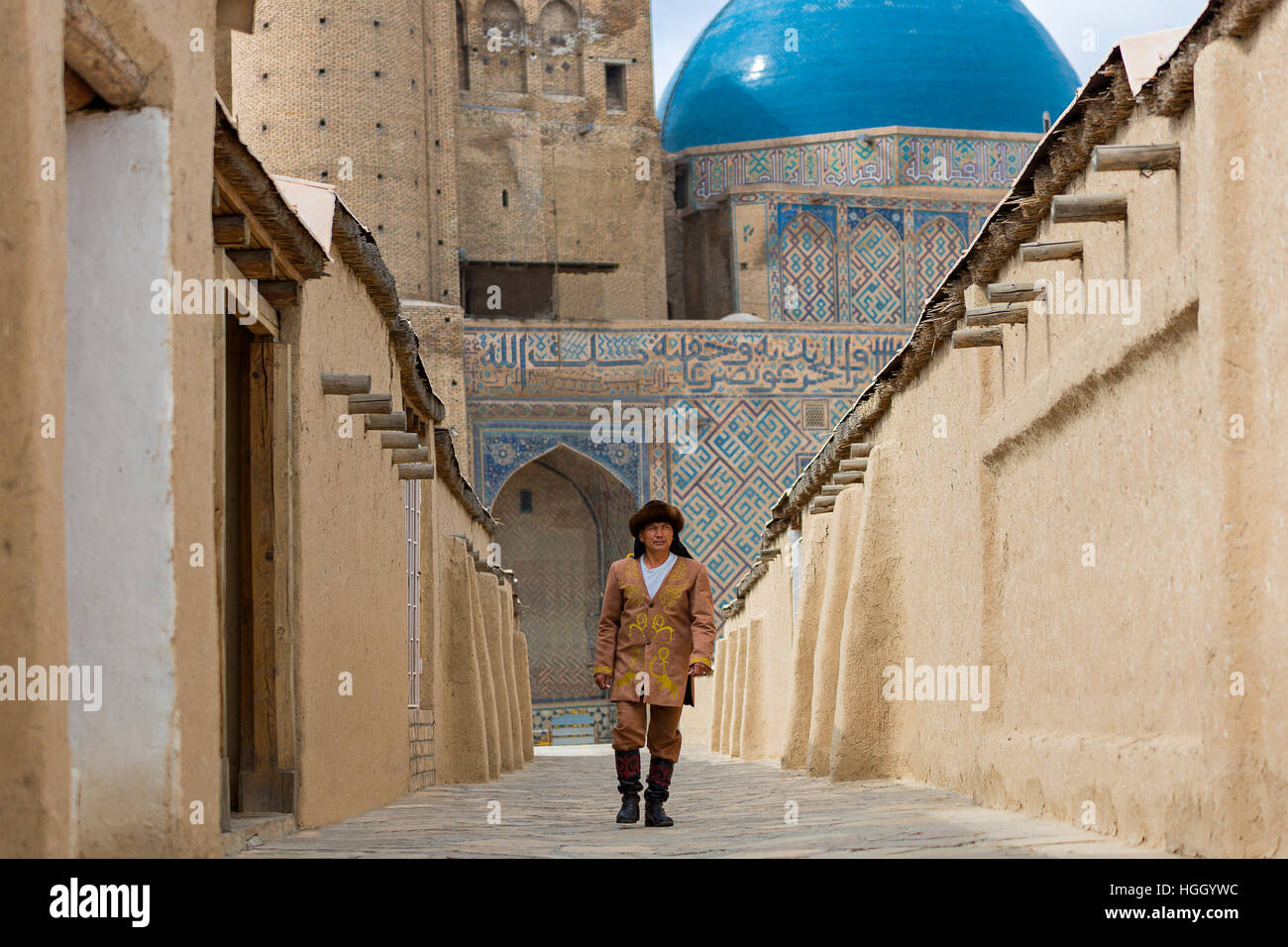 Kazakh man in national costumes with the blue domes of the Khoja Ahmed Yasawi Mausoleum in the background, Turkestan, Kazakhstan Stock Photo