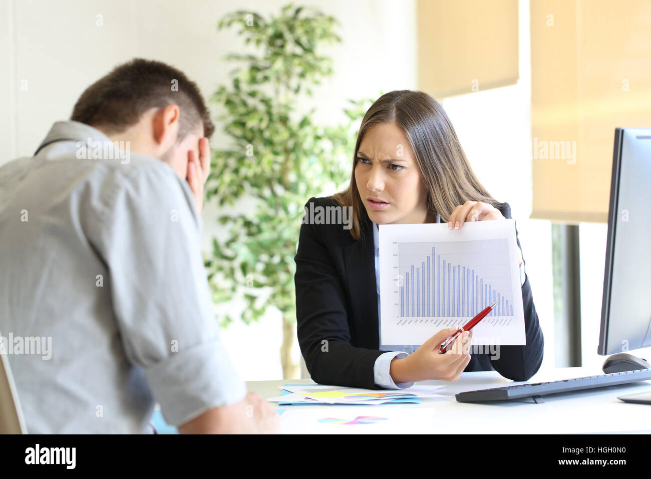 Angry boss showing a growth graph with bad results and scolding to an employee Stock Photo