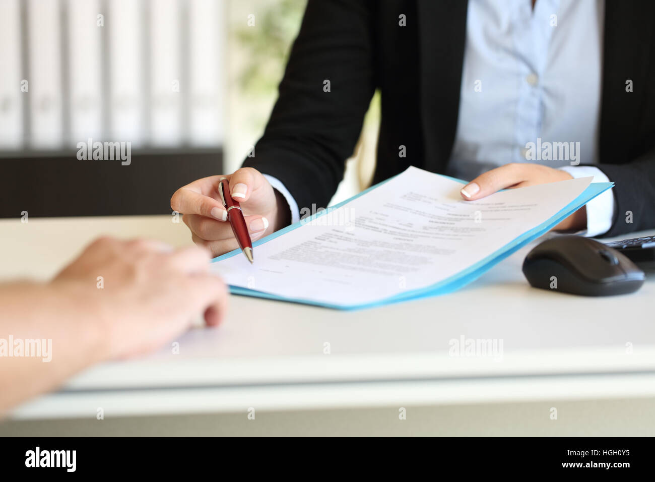 Close up of an executive hands holding a pen and indicating where to sign a contract at office Stock Photo