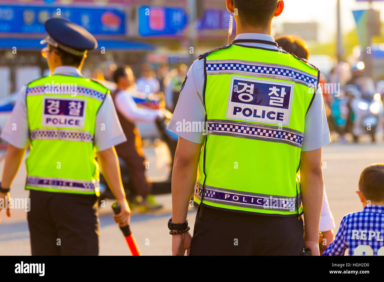 Rear of two Korean policemen in bright vest uniform, written police on back, controlling a demonstration on downtown street Stock Photo