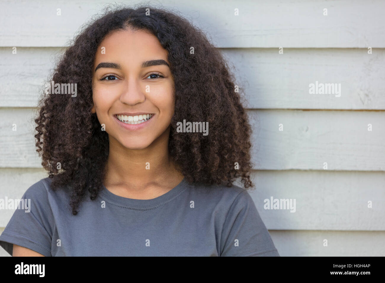 Outdoor portrait of beautiful happy mixed race African American girl teenager female child smiling with perfect teeth Stock Photo