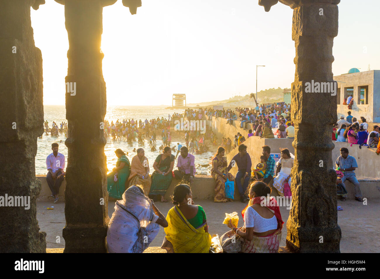 Indian people, tourists leisurely sitting around beach near 16 legged mandap pavilion at evening. Horizontal Stock Photo