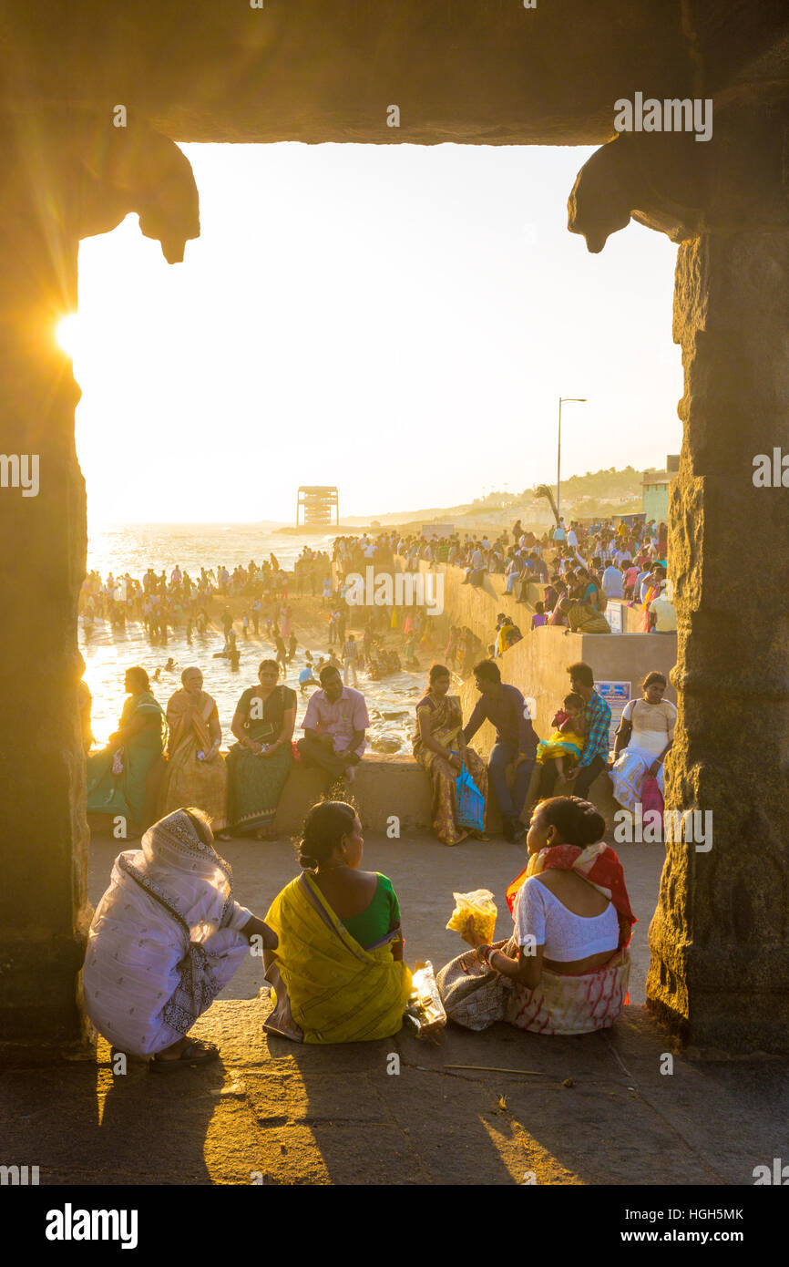 Indian people, tourists leisurely sitting and relaxing around beach near 16 legged mandap pavilion at evening. Vertical Stock Photo
