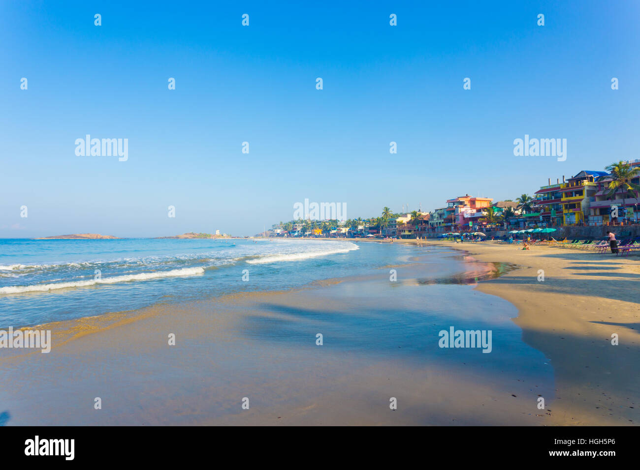 Hotels line the waterfront above the sand beach and ocean waves at a tourist town in Kerala, India. Horizontal Stock Photo