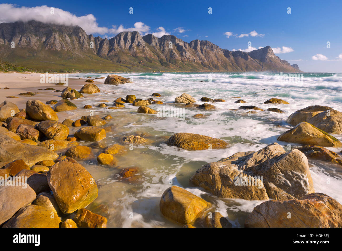 A rocky beach at the Kogel Bay in South Africa with the Kogelberg Mountains in the back. Photographed on a very windy but sunny day. Stock Photo