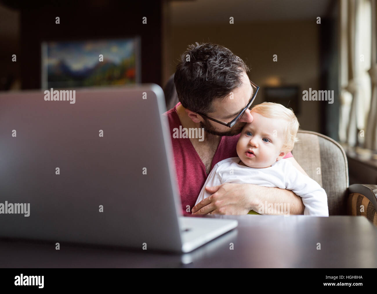 Man with notebook in cafe holding and kissing his son Stock Photo