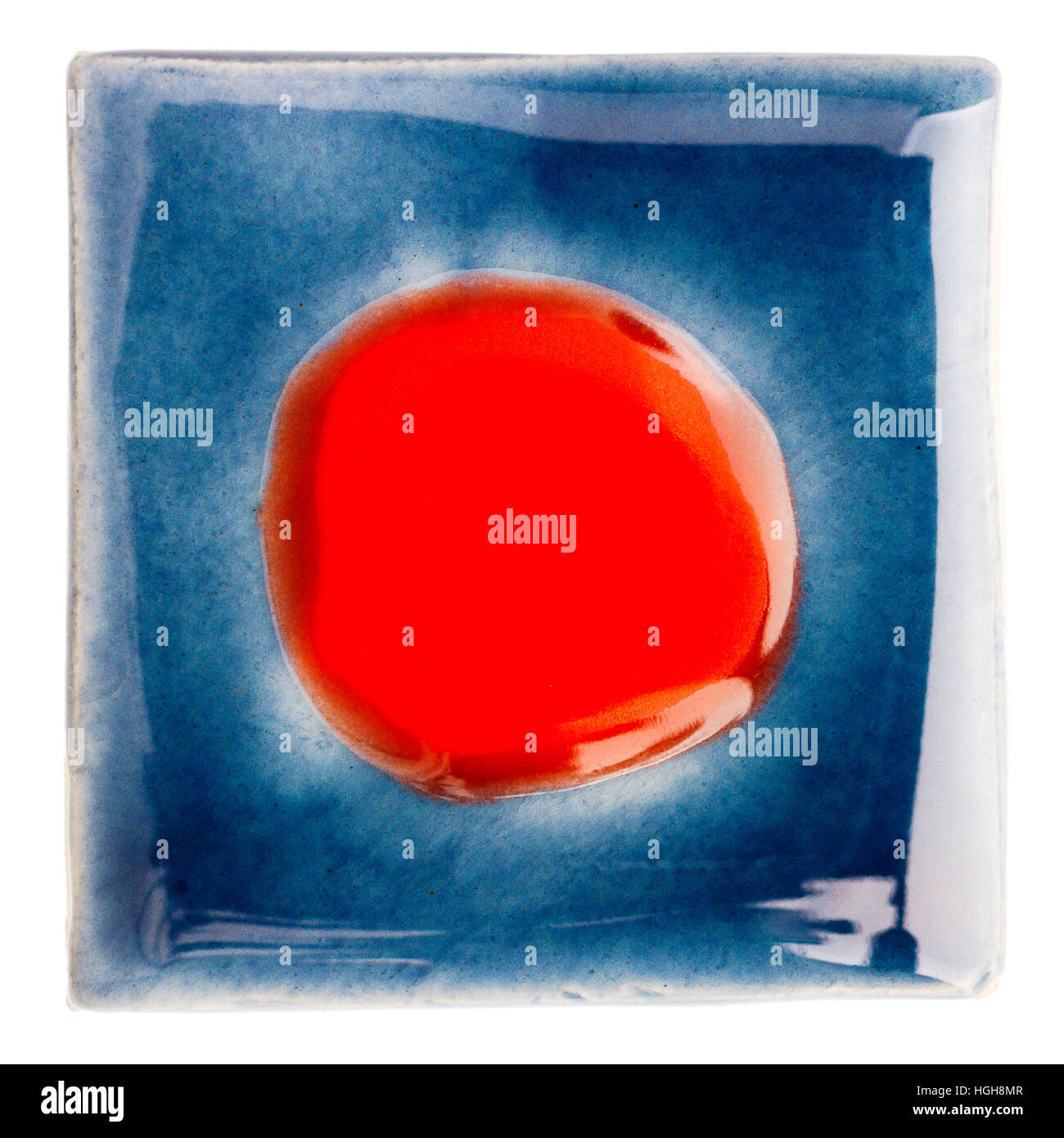 Blue handmade glazed ceramic tile with a dot in middle isolated on