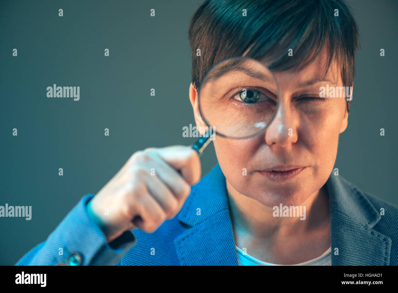 Female tax inspector with magnifying glass looking into papers and documents Stock Photo