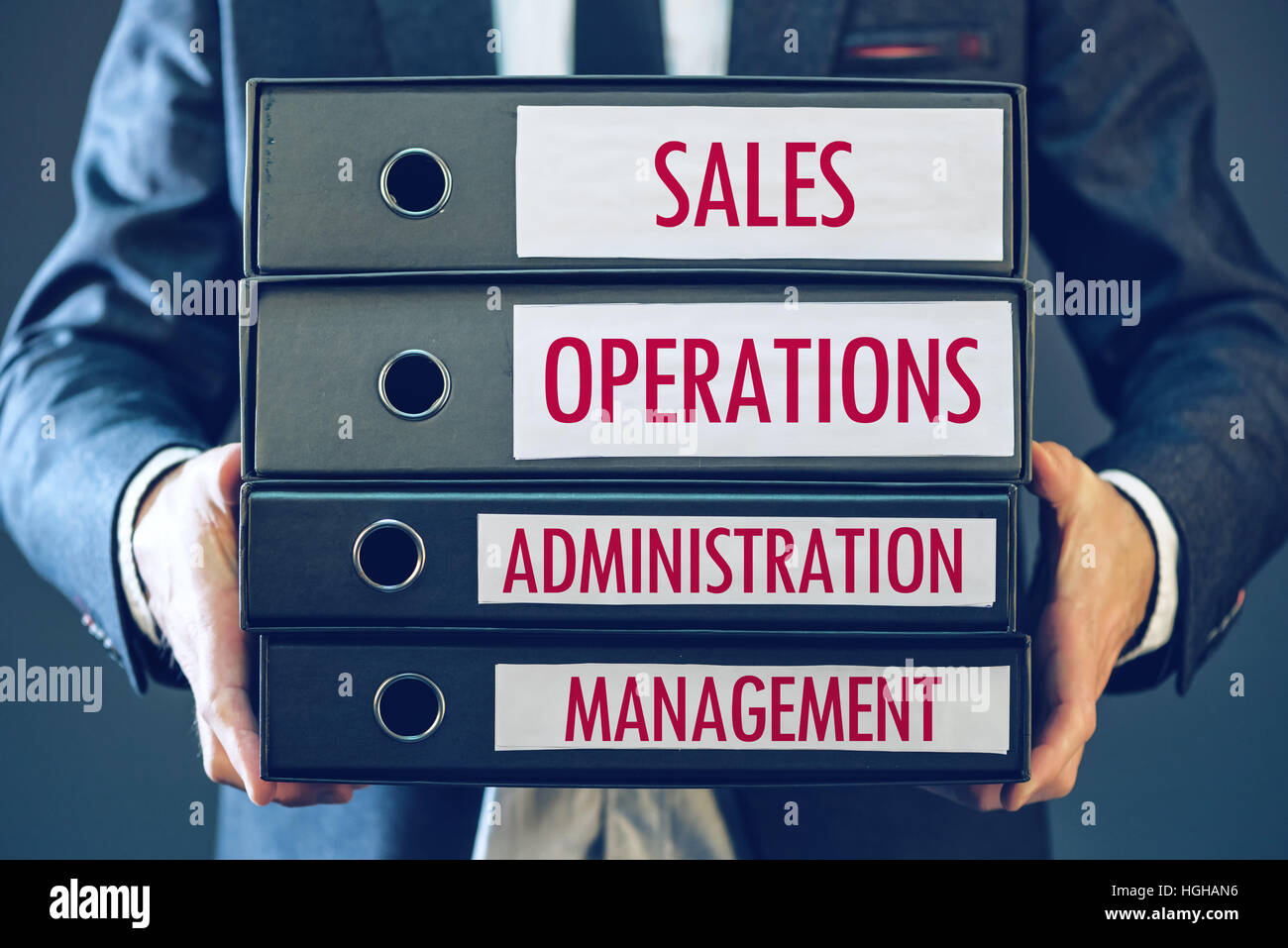 Four core business functions - sales, operations, administration and management with businessman holding ring binders Stock Photo