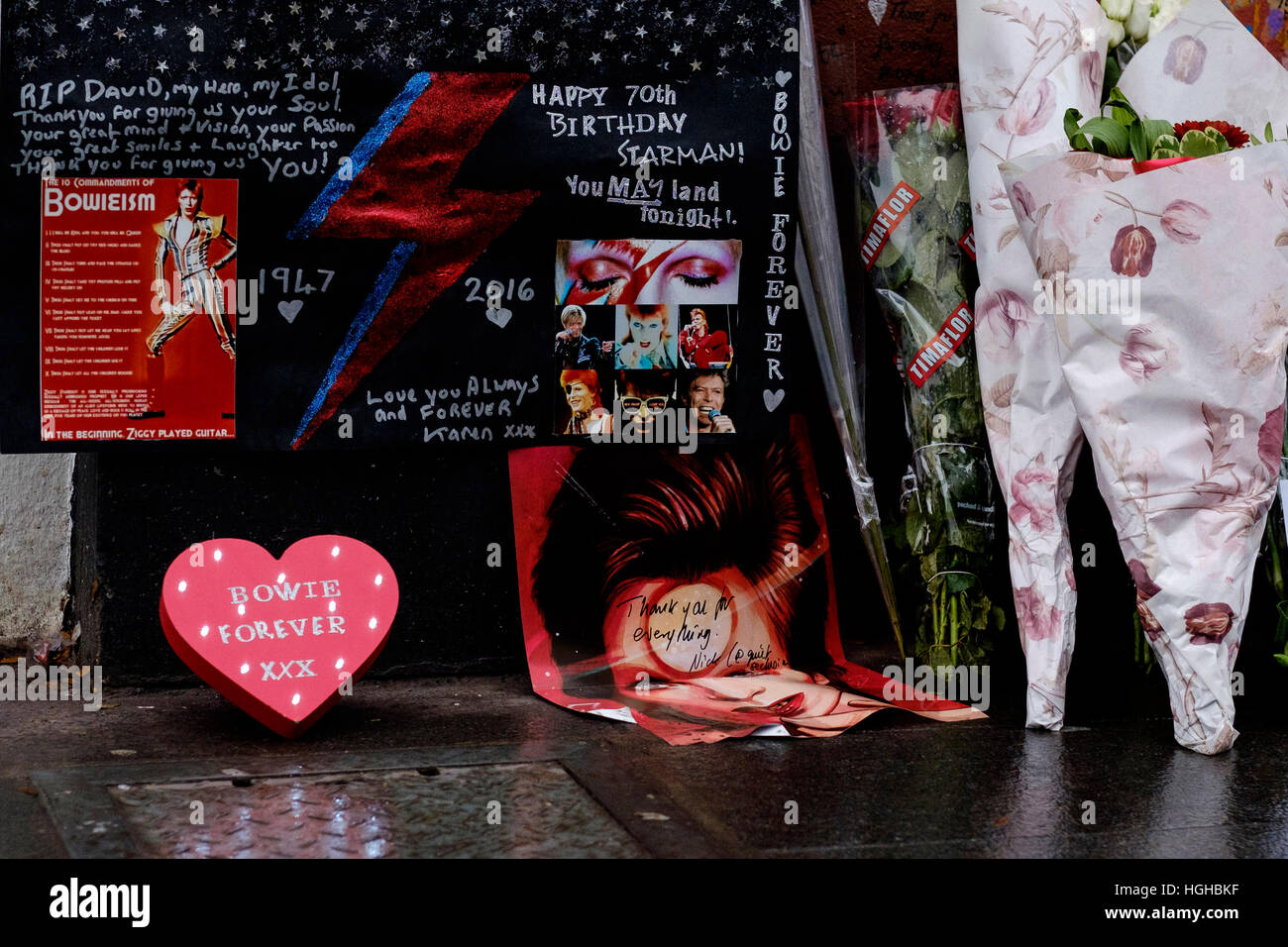 Tributes at the David Bowie Memorial Mural on what would have been his 70th birthday on 08/01/2017 at Brixton, . Pictured: Fans wrote notes, lit candels and left flowers for Bowie who dies almost a year ago. His final album 'Blackstar' was released exactly a year ago on his 69th birthday. Stock Photo