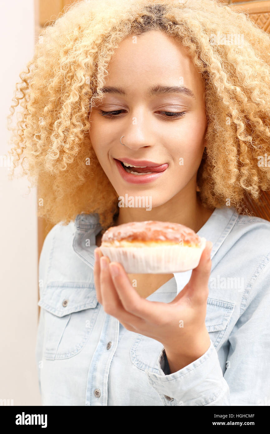 Teenager them a donut. Young girl licks his lips at the sight of tasty donut with icing Stock Photo