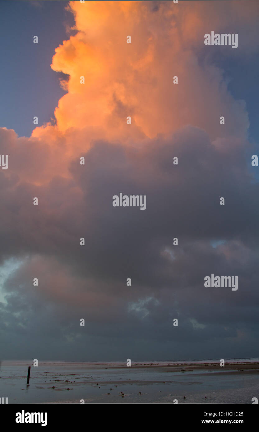 Beach with beach pole, big red cloud at sunset Stock Photo Alamy