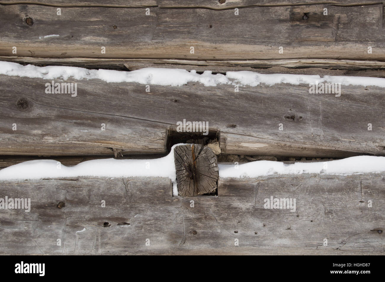 A festive winter background with closeup weathered silvery grey horizontal sawn logs with snow in between. Stock Photo