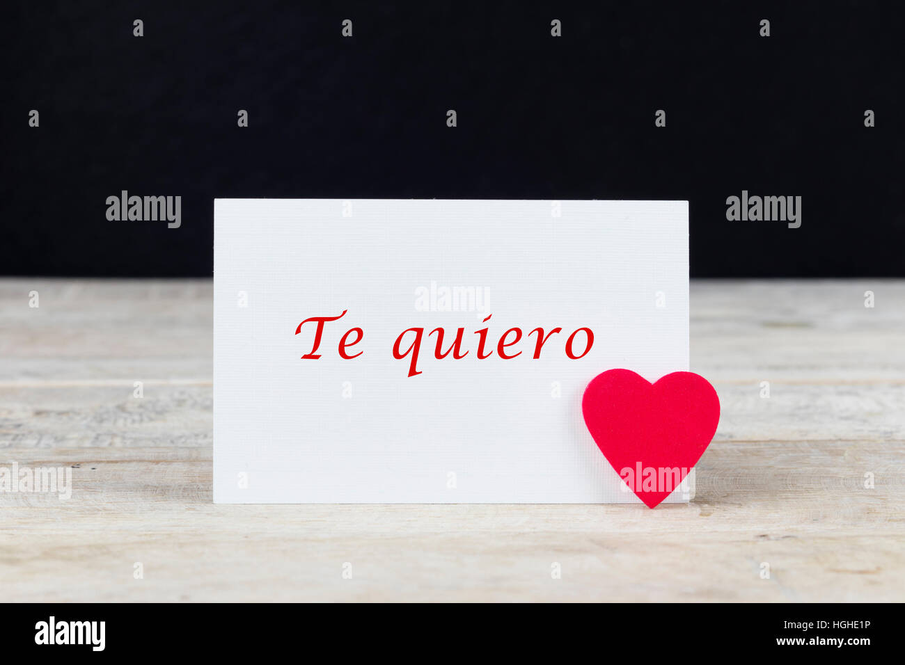 Valentine greeting card on wooden table with text written in spanish 'Te quiero', which means 'I love you'. Stock Photo