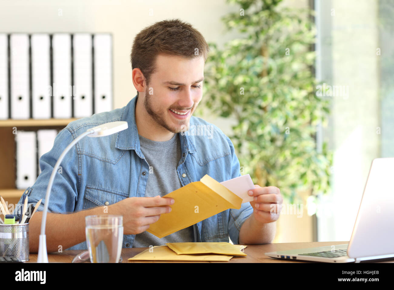 Entrepreneur opening a padded envelope in a desktop at office Stock Photo