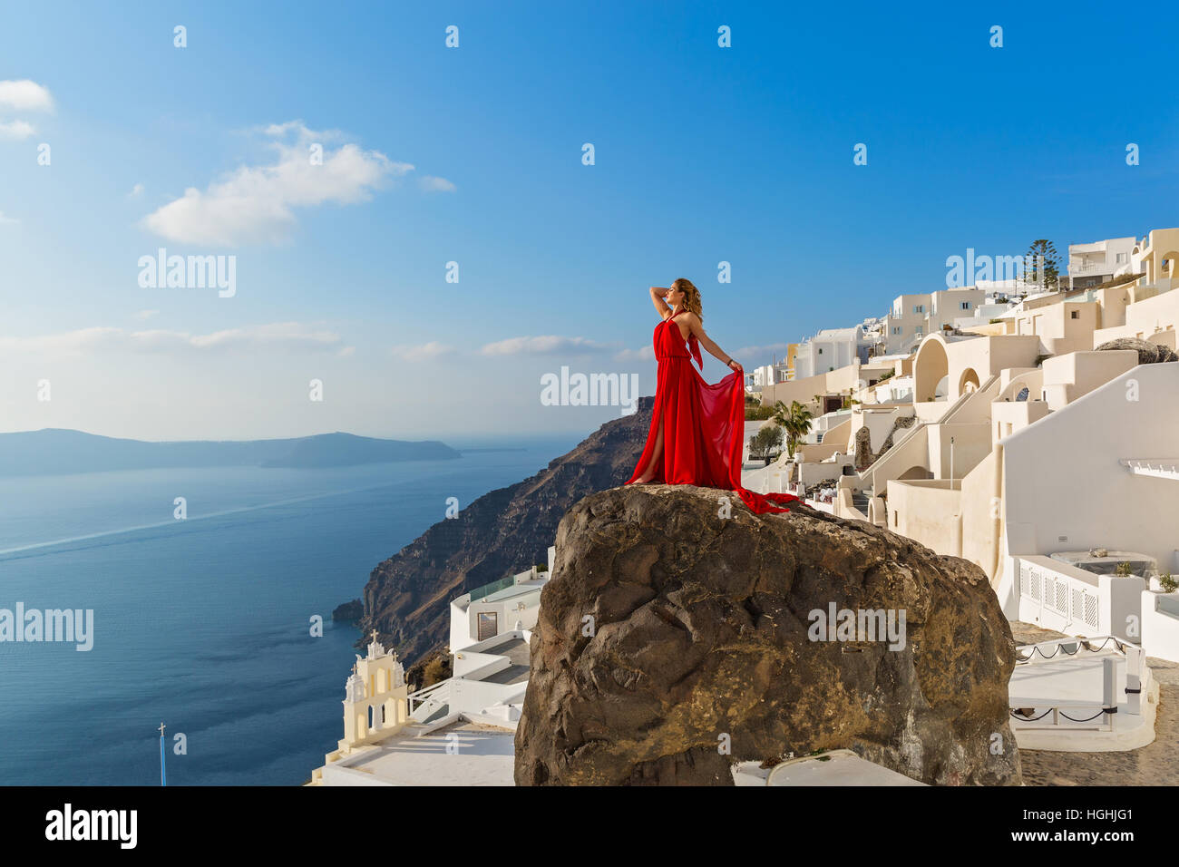 Beautiful woman in red dress stands on a high cliff Stock Photo - Alamy