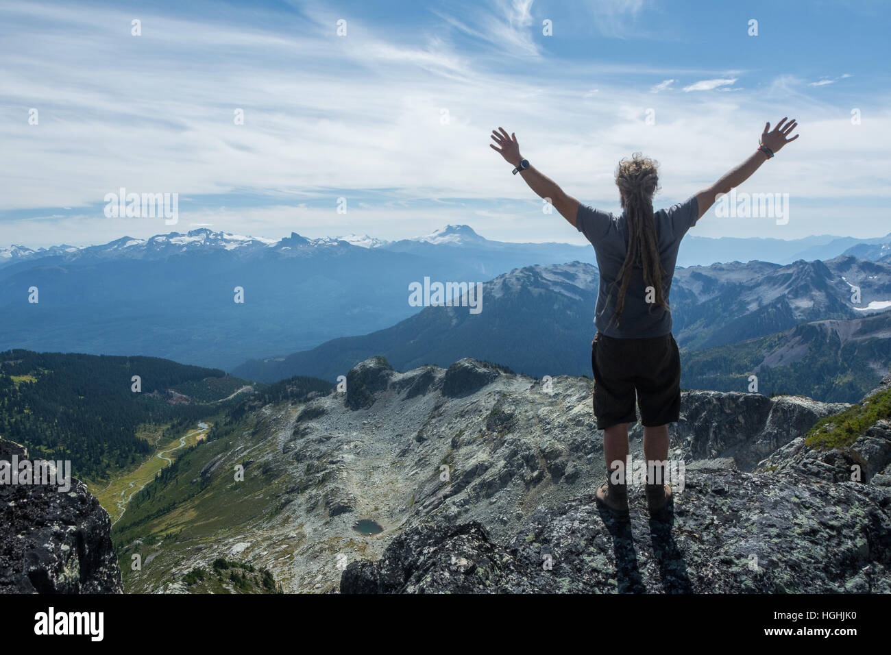 A man looks out over an alpine valley from atop a mountain Stock Photo ...