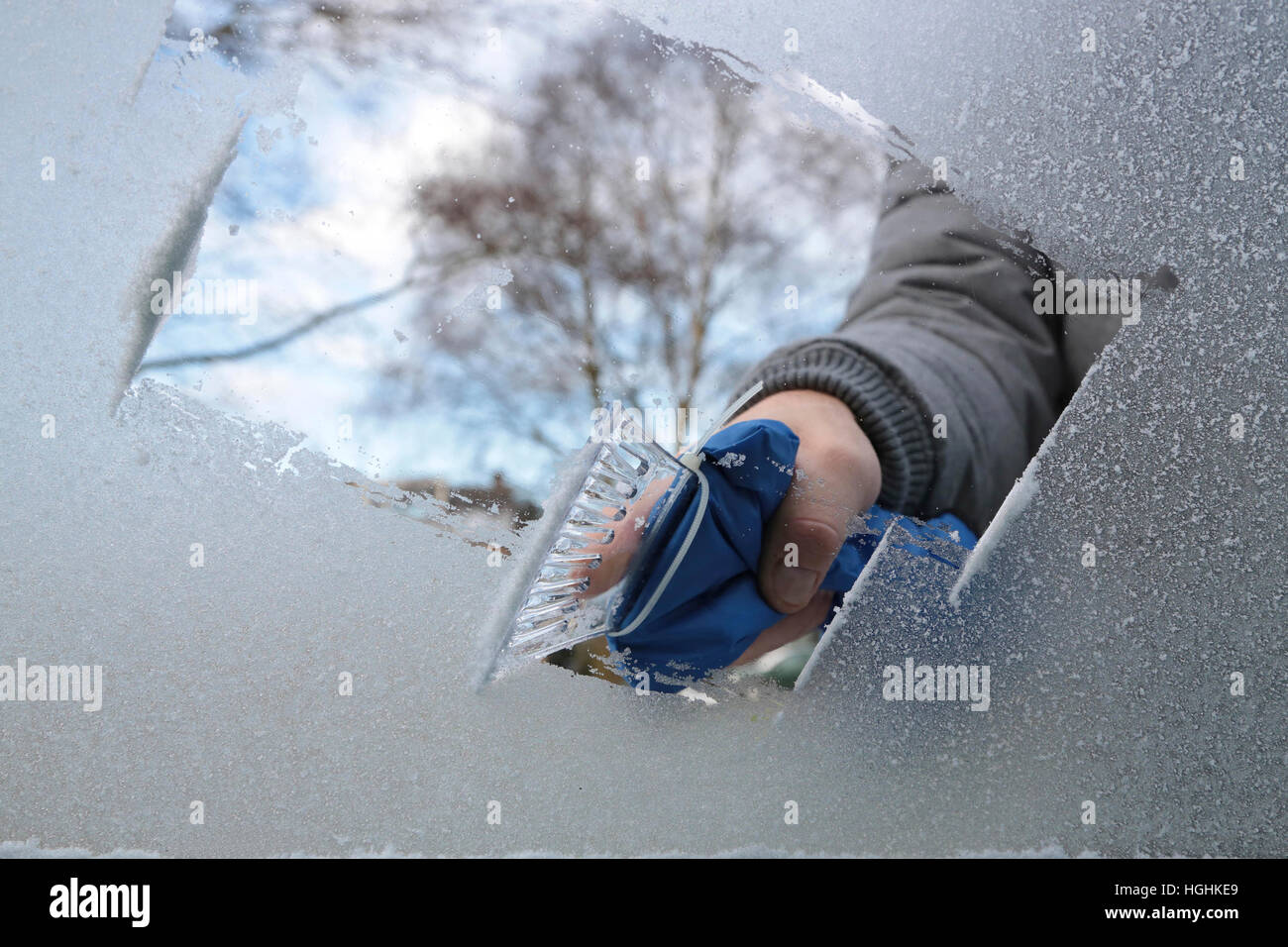 Man removing ice and snow from a car window with a ice scraper Stock Photo Alamy