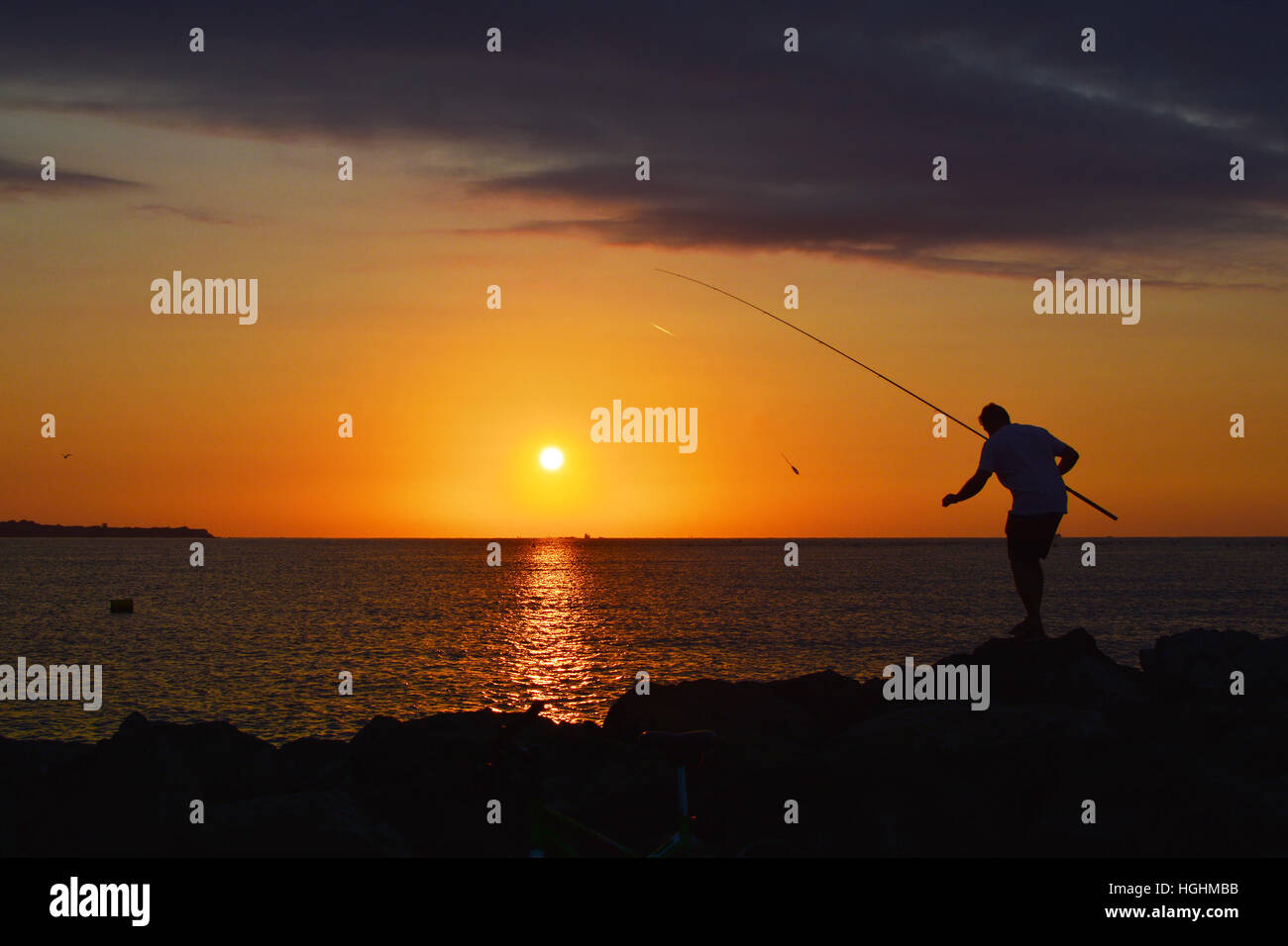 Silhouette of fisherman by the sea on sunrise Stock Photo - Alamy