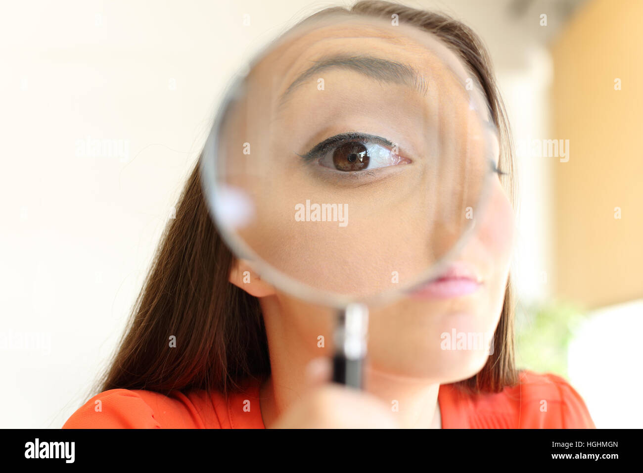 Front view close up of a suspicious businesswoman eye watching you with a magnifying glass Stock Photo