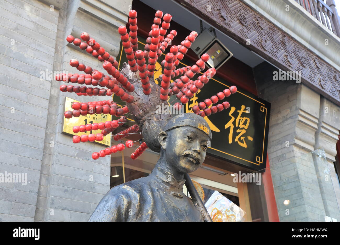 Chinese man statue with sweet apple skewers in Beijing China Stock