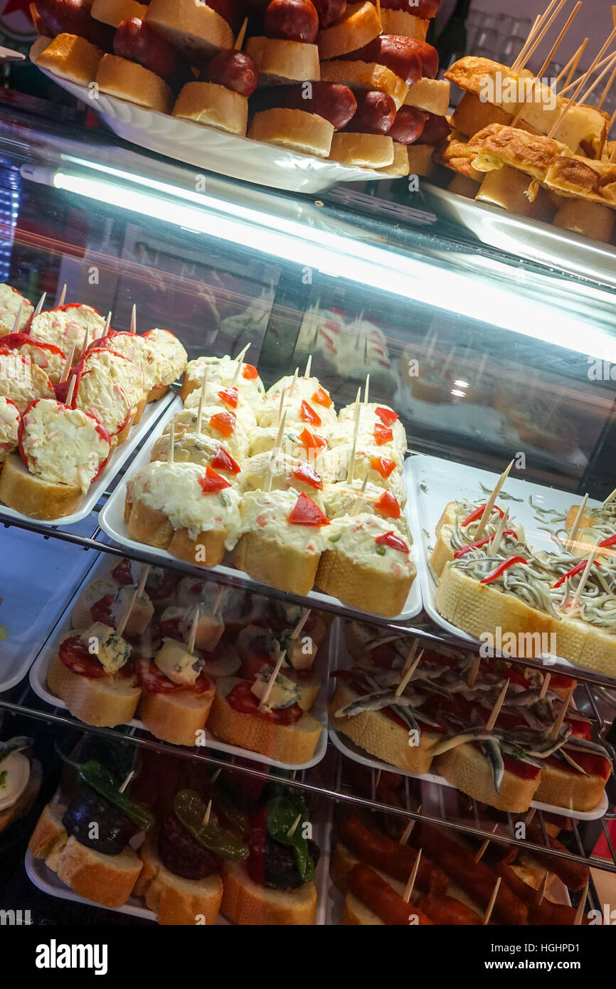 Tapas on display in glass cases on Spanish bar Stock Photo Alamy