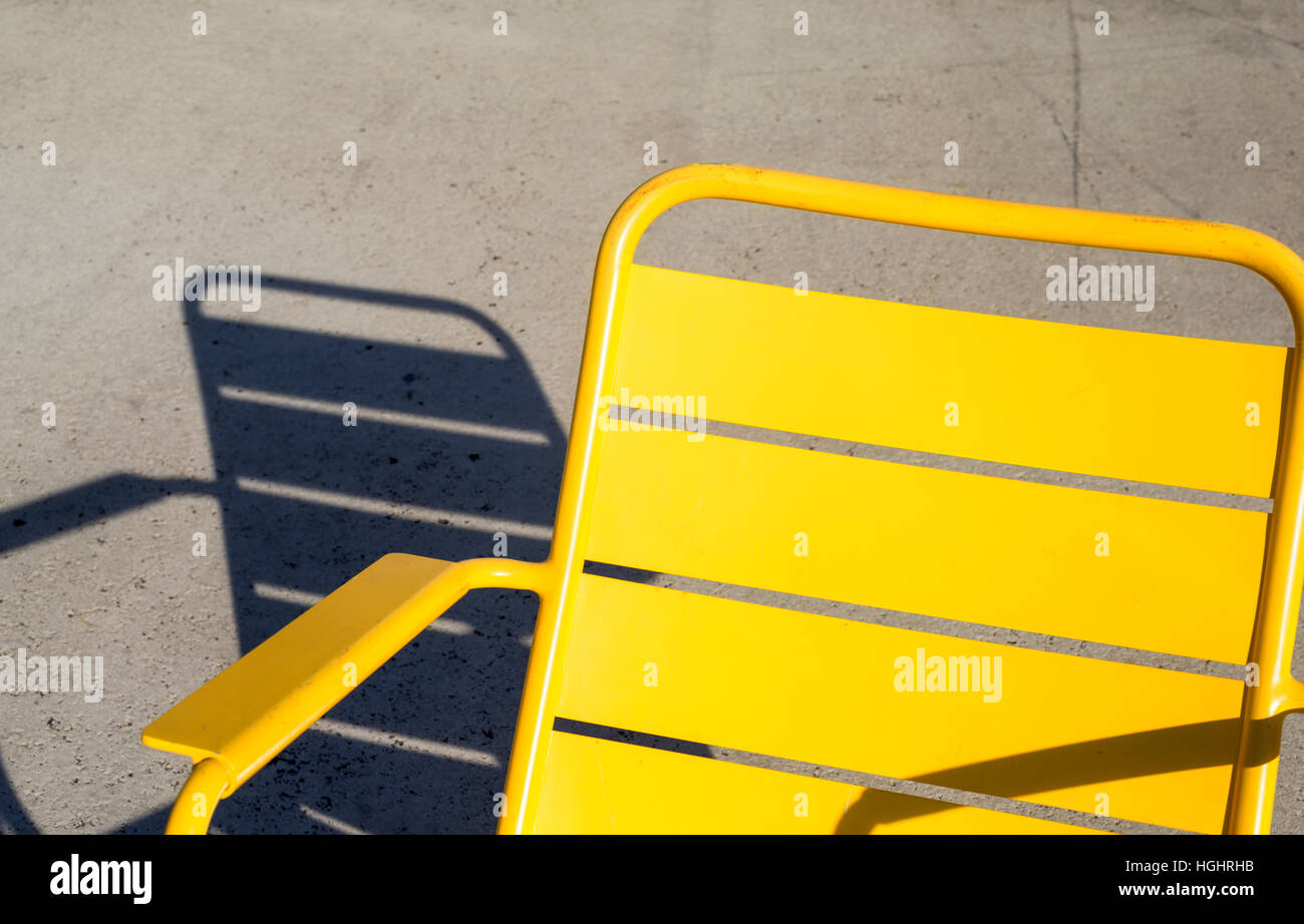 Yellow colored chair and shadow on the ground. Stock Photo