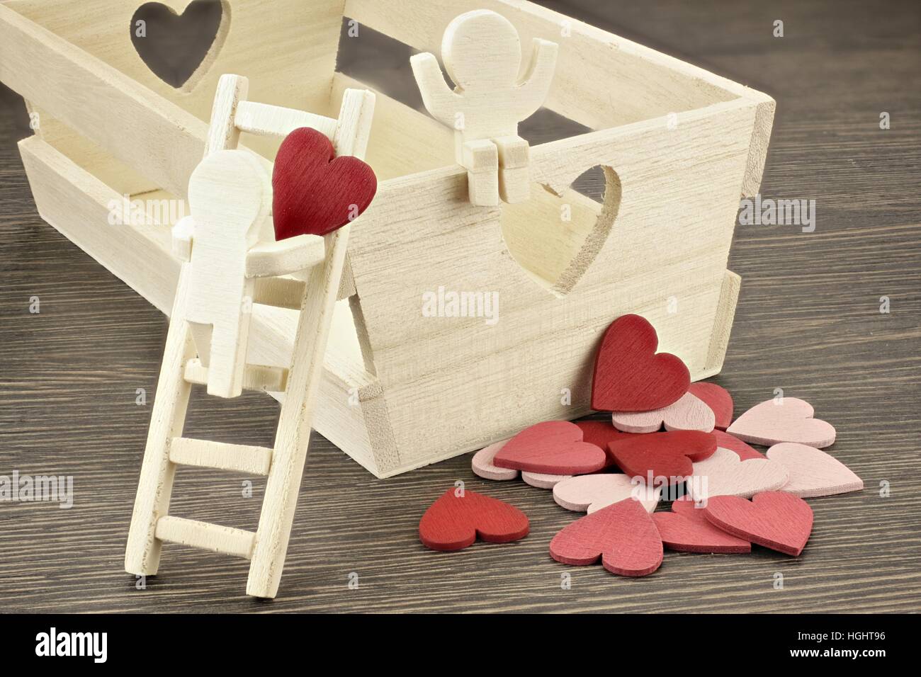 Little wooden figure with heart rises up a  ladder to visit a girl. Symbolic presentation of love and marriage. Stock Photo