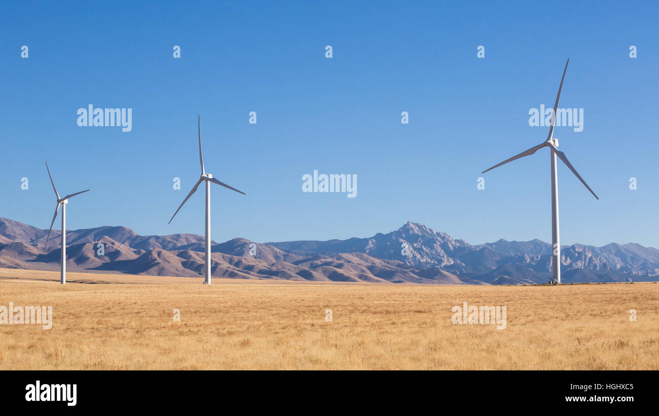 Three windmills are a part of a large wind farm in Southern Utah near the town of Milford. In the background is the iconic Granite Peak of the Mineral Stock Photo