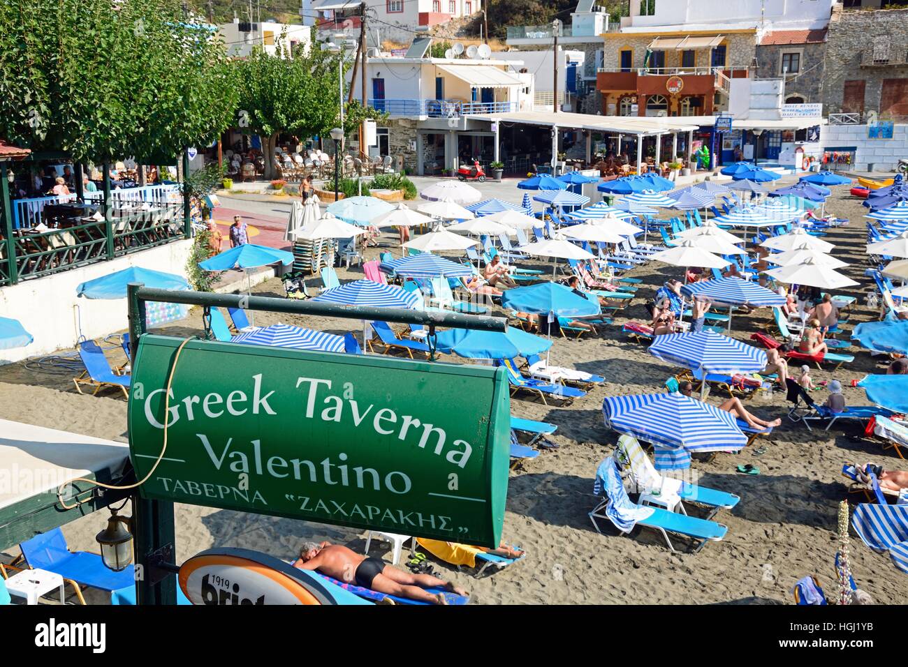 Greek Taverna Valentino sign on the edge of the beach with tourists  relaxing to the rear, Bali, Crete, Greece, Europe Stock Photo - Alamy