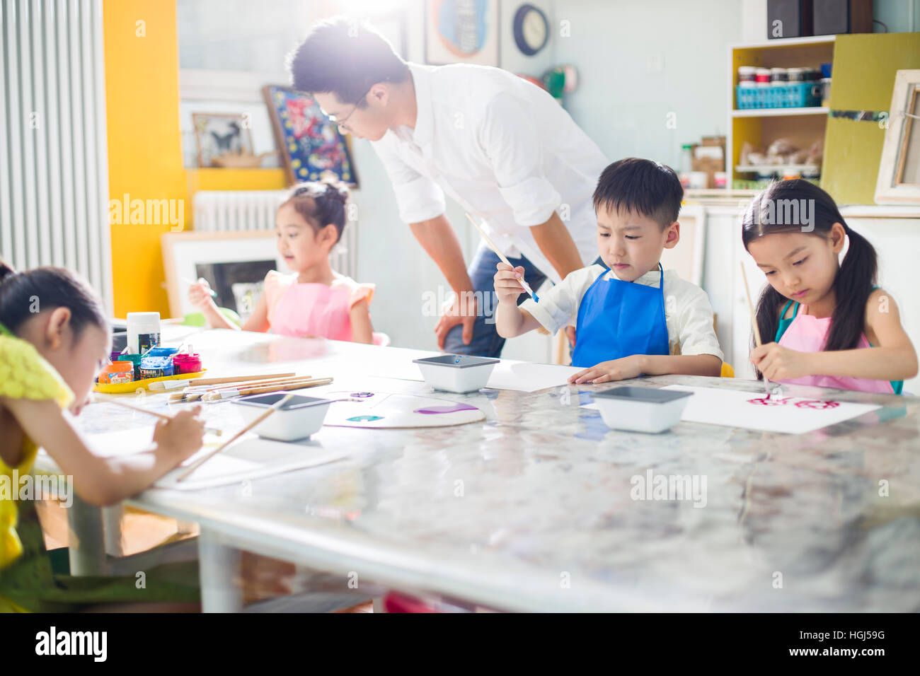 Little children painting in art class with teacher Stock Photo - Alamy