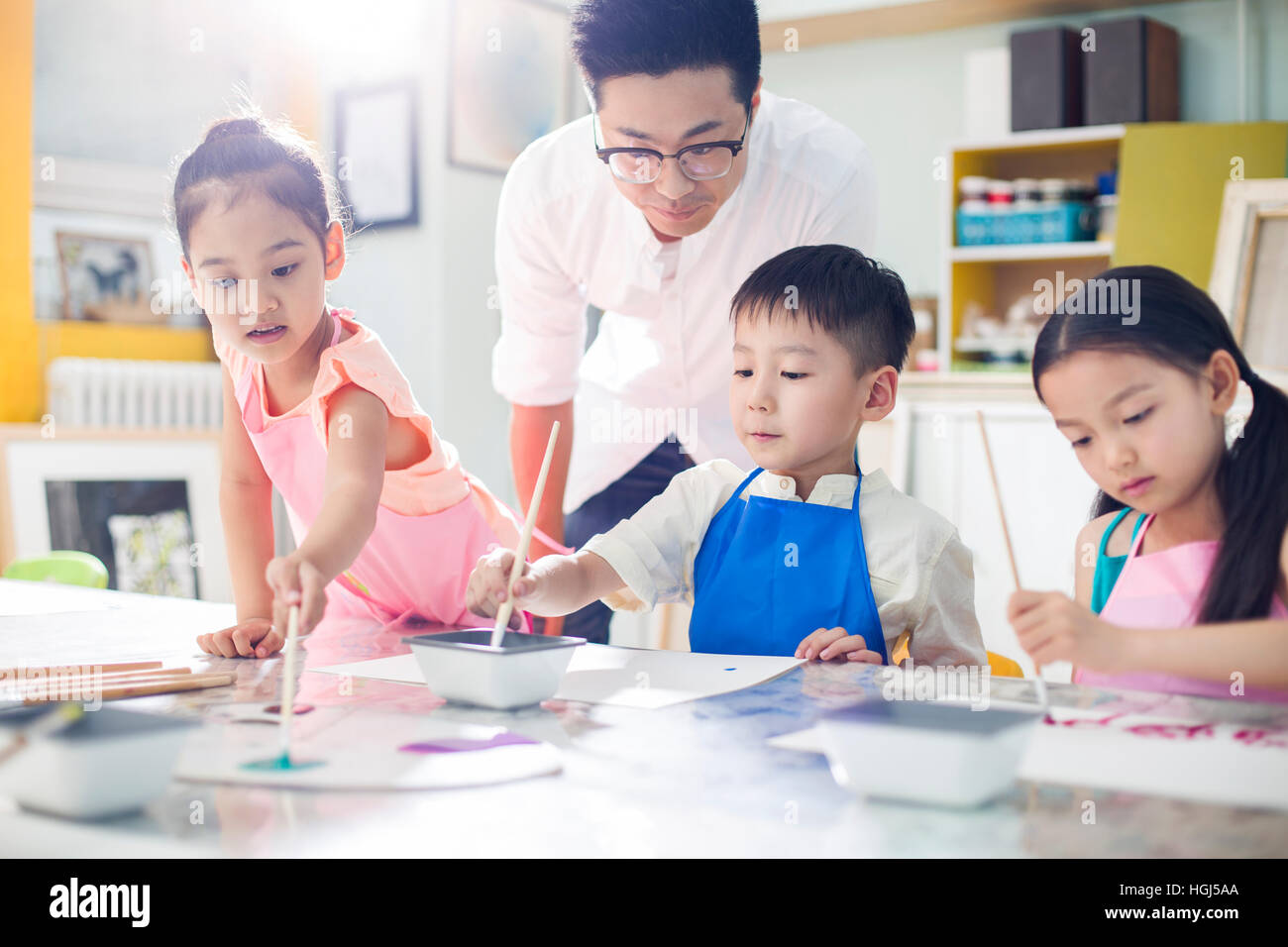 Little children painting in art class with teacher Stock Photo - Alamy