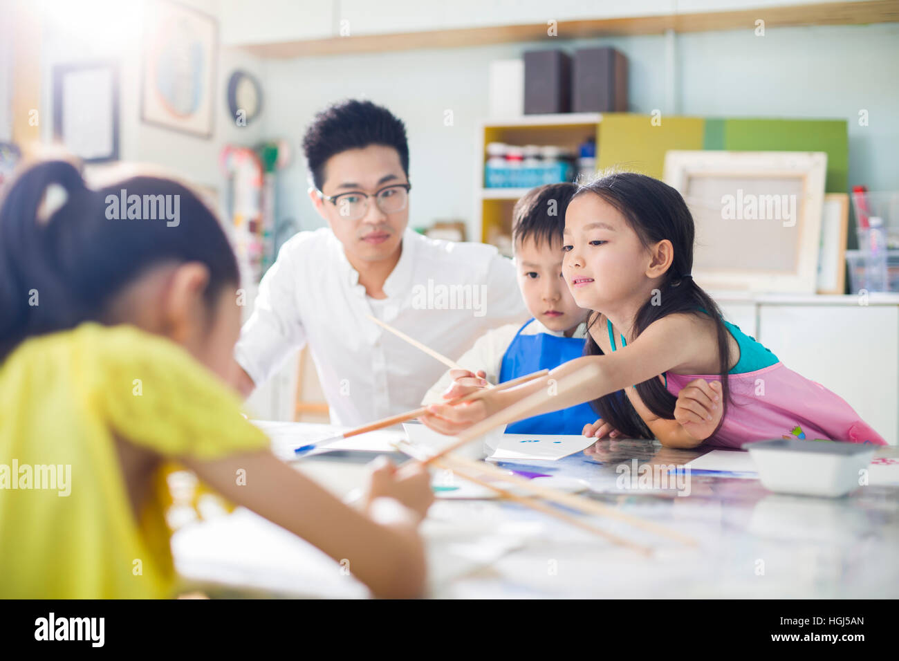 Little children painting in art class with teacher Stock Photo - Alamy